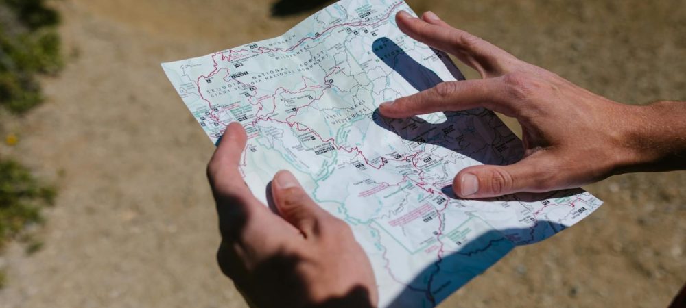 Close-up of hands holding a map during an outdoor adventure on a sunny day.